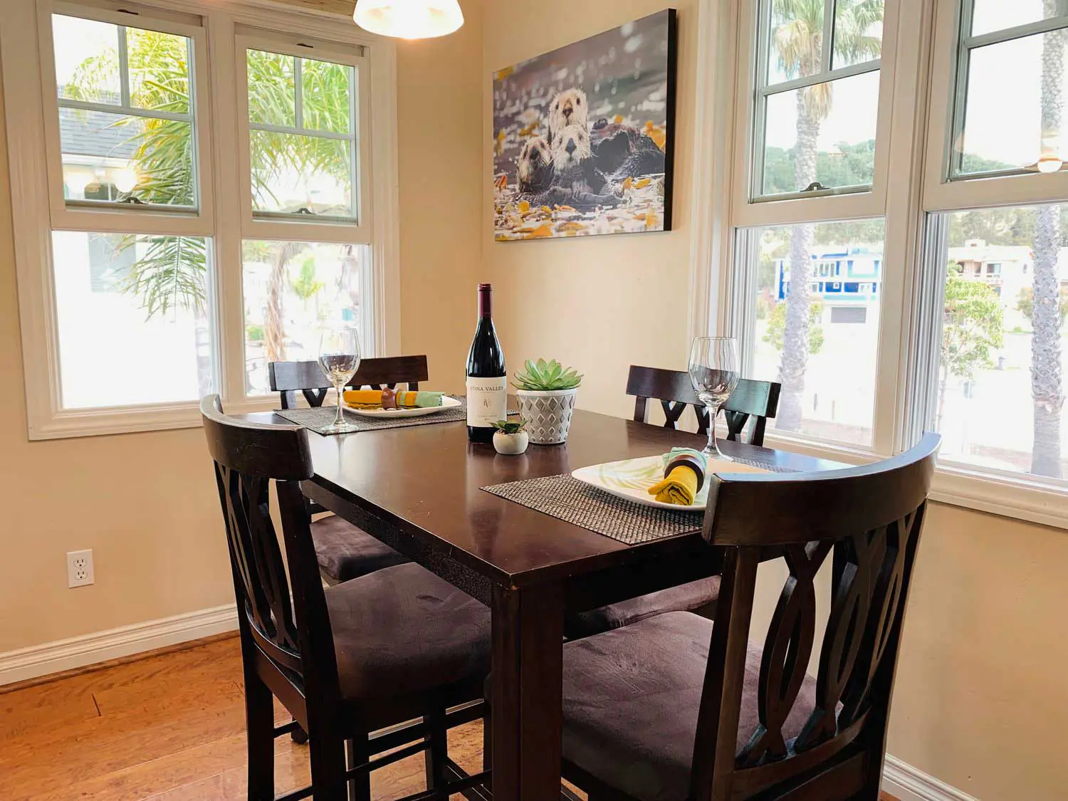 Dining table at Otter Loft I set with wine glasses beneath tall windows