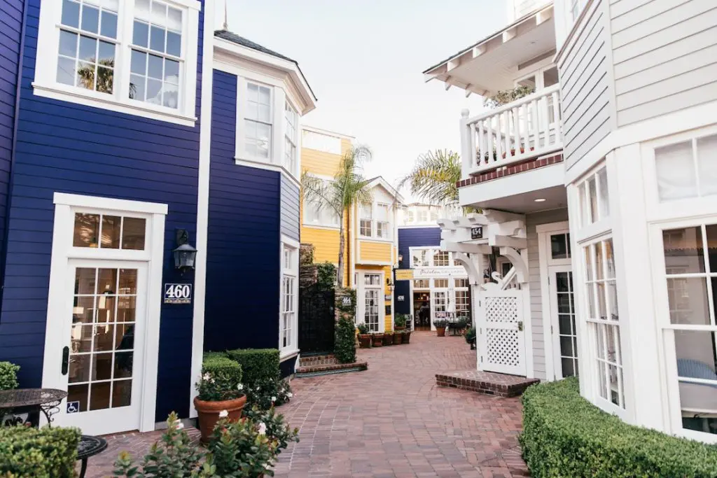 A brick walkway between the navy, yellow and white shopfronts of the Avila Beach village
