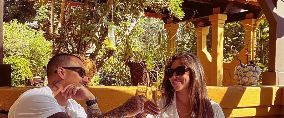 A couple toasting with sparkling wine over breakfast on the sunlit terrace at Sycamore Mineral Springs
